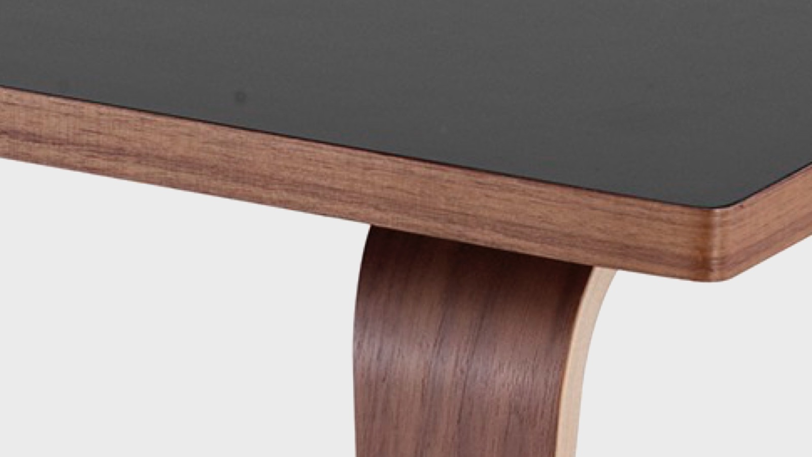 A close-up of the black laminate on top of a coffee table with walnut wood top and molded plywood legs.