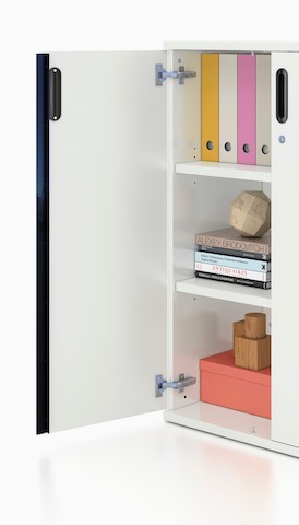Partial view of an open hinged-door Paragraph Storage unit, showing books and binders inside. Select to go to the Storage product page.