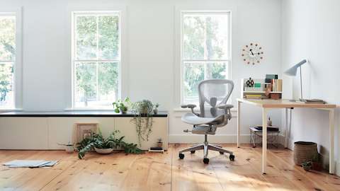Aeron Chair in mineral seen from the front next to an Everywhere Table in a brightly lit home setting.