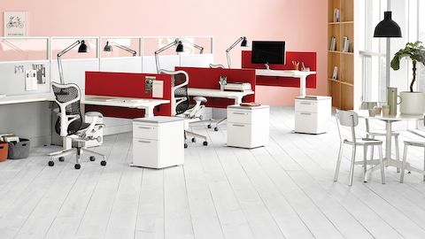 Mirra 2 sillas de escritorio ergonómicas en una oficina abierta en Action Office Estaciones de trabajo con pantallas divisorias de tela roja e iluminación de tareas.