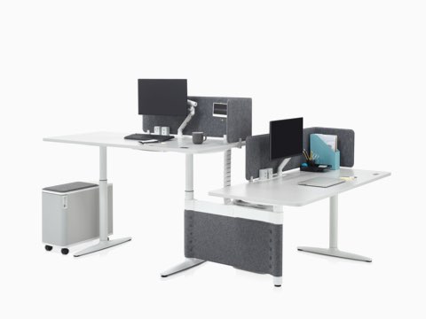 Height-adjustable Atlas Office Landscape desks in a 90-degree configuration, one at standing height and one at seated height.