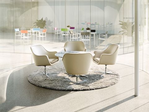 Four white leather Bumper lounge chairs surround a round table.