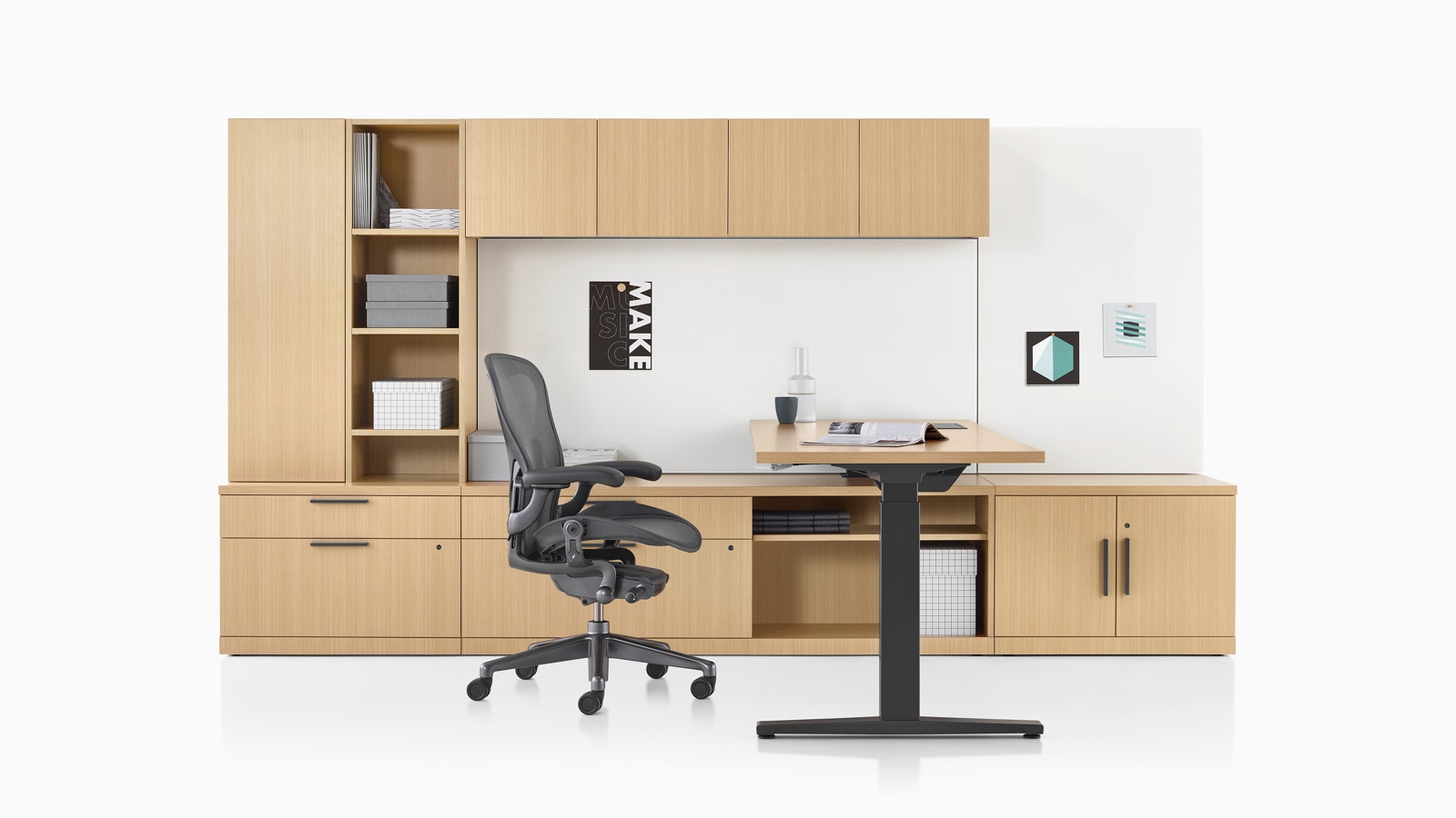 Canvas Private Office con almacenamiento de madera clara, escritorio de altura ajustable, y silla para oficinas Aeron negra.