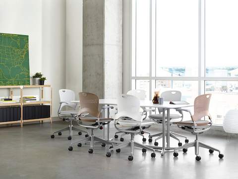 White and light brown Caper Multipurpose Chairs surround a rectangular Everywhere Table in a meeting room.