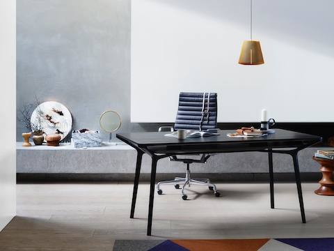 A residential setting featuring a black Carafe Table used as a work desk and paired with a black office chair.