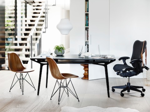 A residential setting featuring a black Carafe Table complemented by a black Mirra 2 office chair and two Eames Moulded Wood Chairs.