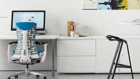Blanco Tu Armarios de almacenamiento y archivos laterales que se muestran con una silla de oficina Embody azul en una estación de trabajo abierta.