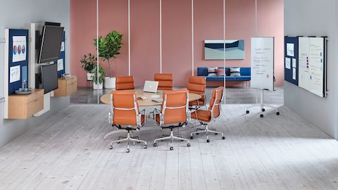 A teardrop Exclave conference table surrounded by six burnt orange Eames Soft Pad Chairs. Select to go to our conference tables pages.