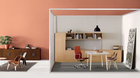 Una oficina privada con una silla Eames Aluminum Group naranja y Canvas Office Landscape storage. Seleccione para ir a nuestra página de oficinas privadas.