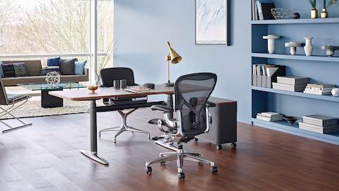 A black Aeron office chair paired with an Atlas Office Landscape desk in a private office with lounge seating and a window wall. Select to go to our private office page.