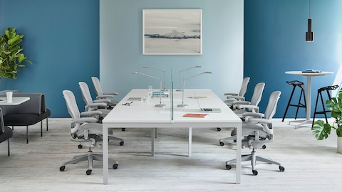 Sillas Aeron en gris claro alrededor de una mesa Layout Studio en blanco.