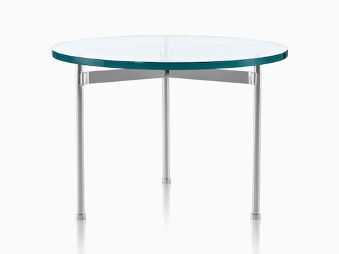 A glass-top Claw Table with a round surface and three metal legs. 