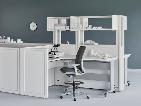 Soft white Co/Struc System with a height-adjustable process table and a dark gray Verus Stool in a medical laboratory.