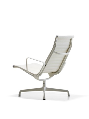 Three-quarter rear view of a white Eames Aluminum Group lounge chair.