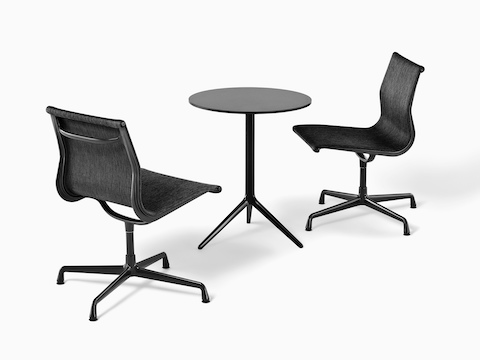 Two armless Eames Aluminum Group outdoor side chairs in a black weave fabric paired with a round black table.
