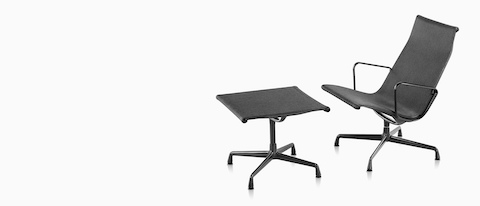 Un Eames Aluminum Group silla de salón al aire libre y otomana en un tejido negro tejido.