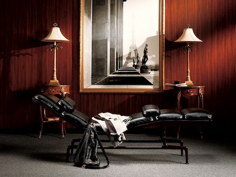 Profile view of a black leather Eames Chaise in a luxurious residential setting. 