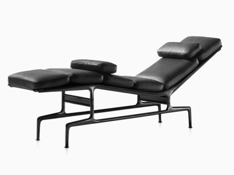 An Eames Chaise with black leather upholstery and a black frame, viewed from a 45-degree angle. 