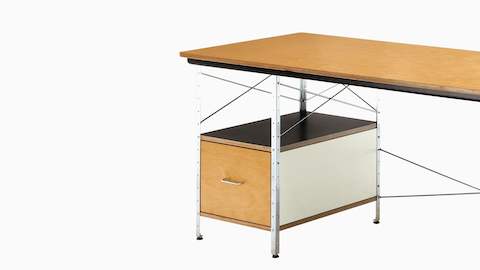An angled view of an Eames Desk in a neutral color scheme, emphasizing the steel cross-supports and file drawer.