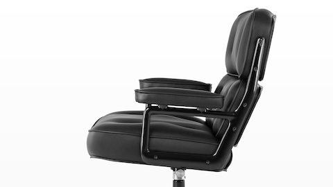 Vista de perfil de una silla ejecutiva de cuero negro Eames, que muestra el asiento, la espalda y los brazos densamente acolchados.