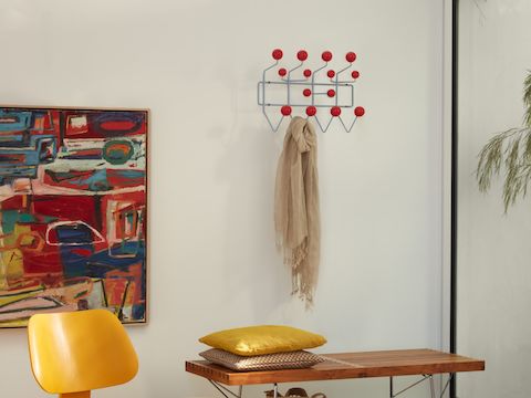 An Eames Moulded Plywood Chair, Eames Hang-It-All storage rack and Nelson Platform Bench with metal legs.