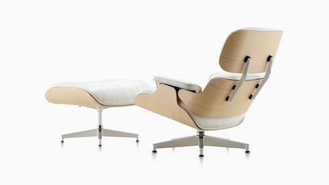 Three-quarter rear view of a white leather Eames Lounge Chair and Ottoman with a white ash veneer shell. 
