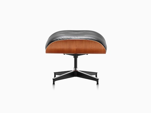 Black leather Eames Ottoman with a wood veneer shell, viewed from the side. 