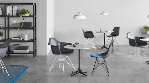Gray Eames Molded Fiberglass Chairs arranged around Nelson Pedestal Tables in a cafe setting.