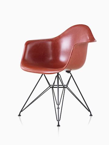A red Eames Molded Fiberglass Chair with arms and a wire base. 