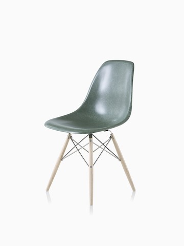 Una silla de visita de fibra de vidrio moldeada Eames con base de clavijas de soporte y asiento en verde oscuro. Seleccione para dirigirse a la página del producto silla de fibra de vidrio moldeada Eames.