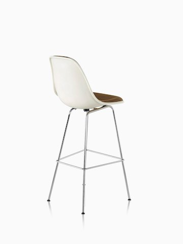 Three-quarter rear view of a white Eames Molded Fiberglass Stool with brown upholstery. 