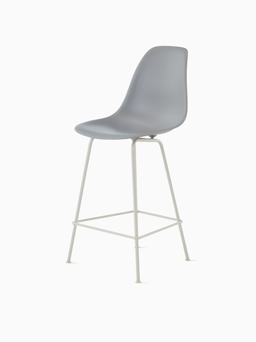 White Eames Molded Plastic Stool with red upholstery, viewed from a 45-degree angle. 