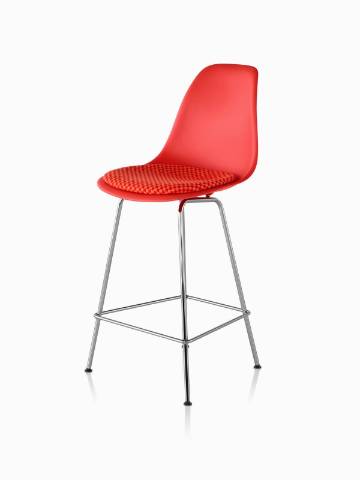 Red Eames Molded Plastic Stool with a red seat pad, viewed from a 45-degree angle. 