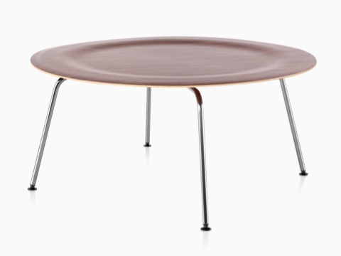 Una mesa de centro de madera contrachapada moldeada redonda de Eames con las piernas del metal y una tapa dentada en un final medio.