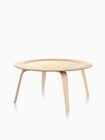 Una mesa de centro redonda de madera contrachapada moldeada de Eames. Seleccione para ir a la página del producto de la mesa de centro de madera contrachapada moldeada de Eames.