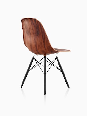 Vista trasera de tres cuartos de una silla lateral de madera moldeada Eames con un acabado oscuro y patas de espiga.