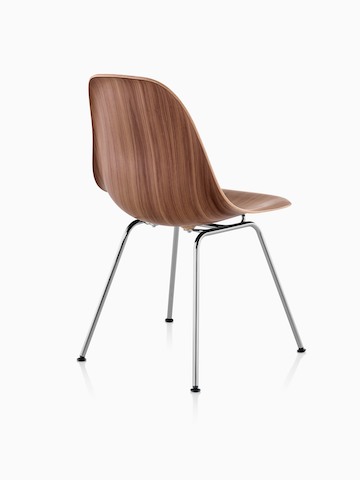 Vista trasera de tres cuartos de la versión de cuatro patas de una silla lateral de madera moldeada de Eames terminada en un tono medio.