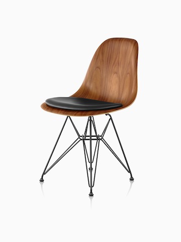 Silla de madera moldeada Eames con un acabado medio, almohadilla negra para el asiento y base de alambre, vista desde un ángulo de 45 grados.