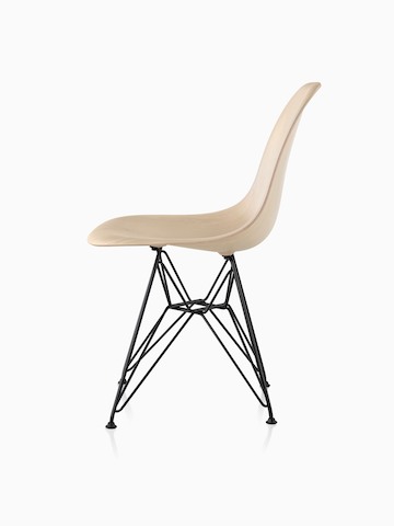 Vista de perfil de una silla lateral de madera moldeada Eames con un acabado ligero y base de alambre.