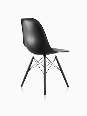 Three-quarter rear view of a black Eames Molded Wood side chair with dowel legs.