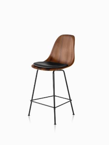 Eames Molded Wood Stool with a dark finish, black leather seat pad, and black legs, viewed from a 45-degree angle. 