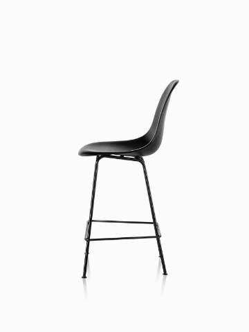 Profile view of a black Eames Molded Wood Stool with black legs. 