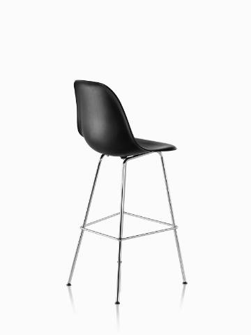 Three-quarter rear view of a black Eames Molded Wood Stool with silver legs. 