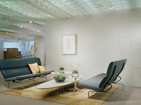 Dos paños de sofá gris Eames uno frente al otro en el vestíbulo de una oficina.