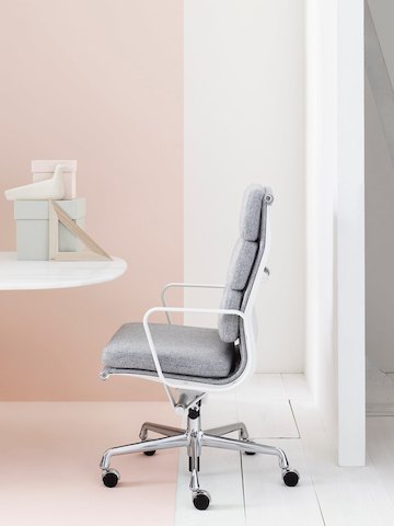 Profile view of Eames Soft Pad high-back executive chair in light gray upholstery.