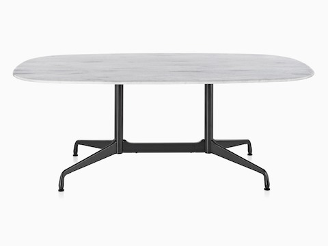 Una mesa ovalada Eames al aire libre con una tapa de mármol blanco y base negra.