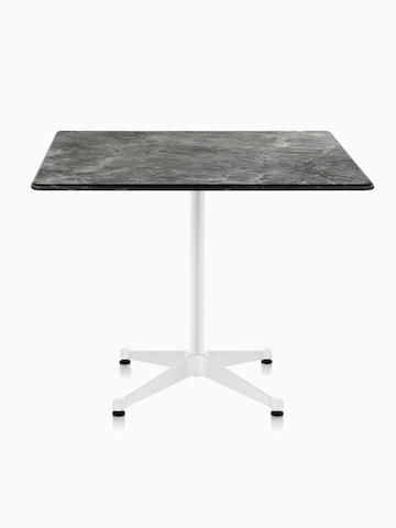 Una mesa cuadrada Eames al aire libre con una tapa de piedra negra y base blanca.