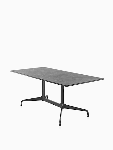 Una mesa rectangular Eames al aire libre con una tapa de piedra negra. Seleccione para ir a la página del producto Eames Tables Outdoor.