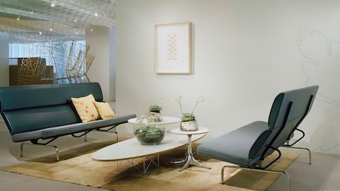 An Eames Wire Base Elliptical Table nestled with two Nelson Pedestal Tables and positioned between two  Eames Sofa Compacts.