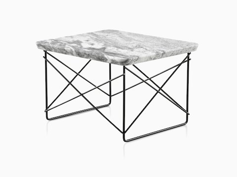 An angled view of a rectangular Eames Wire Base Low outdoor table with a marble top and black wire base. 